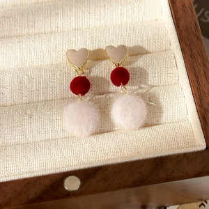 Vue détaillée des clous en cœur dorés avec pompons en peluche doux rouges et blancs