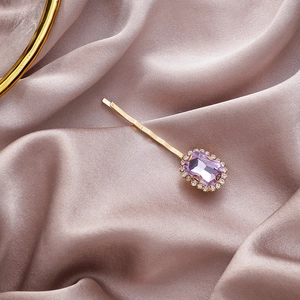 Detailopname van een vintage haarclip met paarse edelsteen en strassteentjes op fluweel