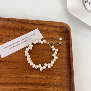 Détail d'un bracelet en perles de culture baroques avec fermoir doré sur bois