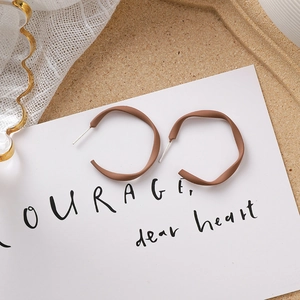 Détail de boucles d'oreilles créoles ondulées marron mat avec tiges en argent