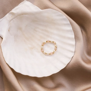 Detailed shot of handmade beaded ring with pearls and crystals on champagne silk fabric