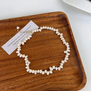 Détail de perles d'eau douce baroques irrégulières sur plateau en bois avec fermoir doré