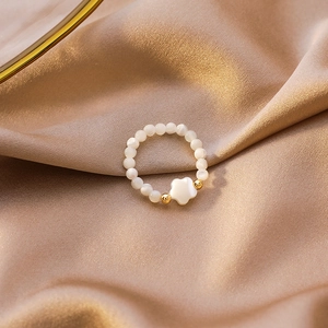 Macro detail of elastic beaded heart ring with mother of pearl beads on satin background