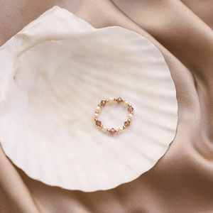 Detail of handmade beaded ring with freshwater pearls and violet crystals on a white shell