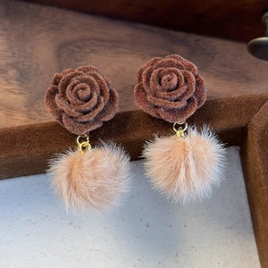 Détail de boucles d'oreilles avec rose en velours et pompon en fausse fourrure douce