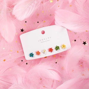Detailed view of six pairs of colorful daisy flower stud earrings on jewelry card