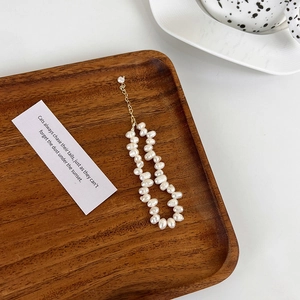 Bracelet en perles d'eau douce baroques et chaîne dorée sur un plateau en bois