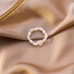 Detailed view of heart shell beaded ring on champagne satin fabric for minimalist jewelry look