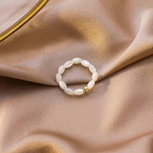 Macro view of beaded heart ring with white shell pearls on champagne silk fabric