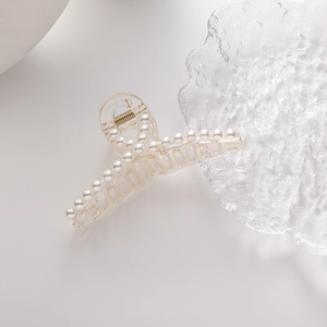 Details von transparenten Haarklammern mit eleganten weißen Perlen und Goldmetallfeder