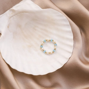 Detail of handmade colorful crystal bead and freshwater pearl ring on a seashell