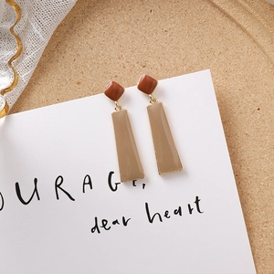 Détail de boucles d'oreilles géométriques vintage en résine marron et pendentif crème