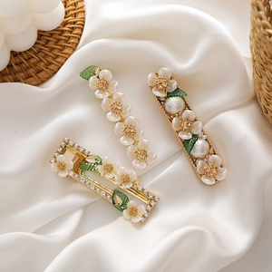 Three-piece floral hair clip set with shell pearls and green leaves on gold metal base