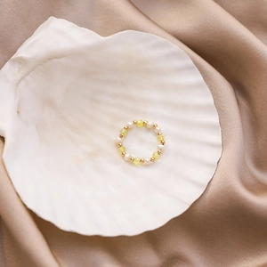 Detail of handmade beaded ring with freshwater pearls and yellow crystals on a shell