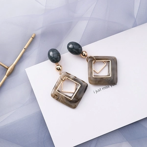 Detail of geometric drop earrings with marble texture and gold metallic accents
