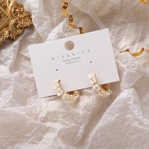 Detailed view of floral C-shaped gold earrings with shell petals and 925 silver needle