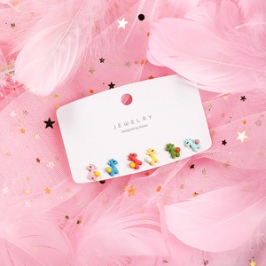 Detailed view of colorful giraffe stud earrings set on dreamy pink feather background