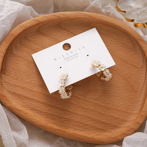 Floral shell earrings with 925 silver posts and gold metal hoops on wood tray