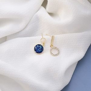 Detail of asymmetric blue crystal cluster earrings with gold ring and zircon embellishments