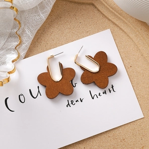 Détail de boucles d'oreilles fleurs en bois marron avec crochets en métal doré