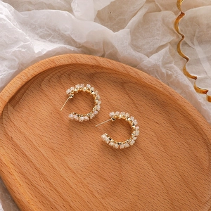 Elegant gold C-shaped hoop earrings with iridescent white shell flower petals