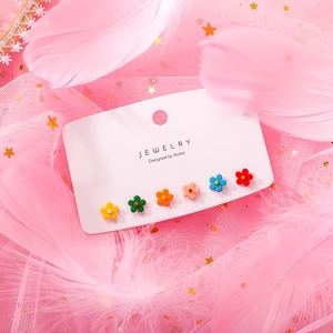 Close-up of six colorful candy-colored flower stud earrings on white jewelry card