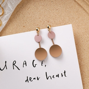 Détail de boucles d'oreilles géométriques avec clous dorés et cercles kaki sur carte