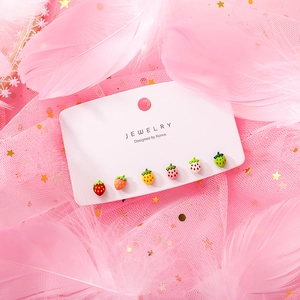 Detail view of 6-pair colorful strawberry stud earrings set on a pink feather background