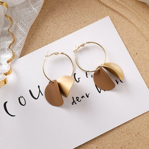 Détail de boucles d'oreilles géométriques marron et beige mat sur carte élégante