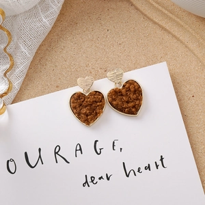 Détail de boucles d'oreilles cœur avec haut en métal doré et pendentif en peluche brune