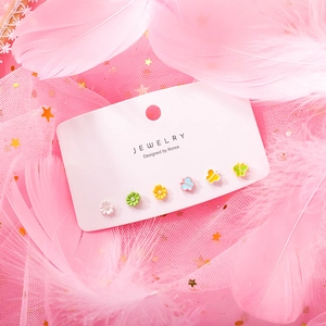 Close-up of 6-piece colorful floral and butterfly stud earring set on pink feathers