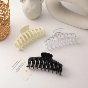 Close-up of cream, transparent, and black hair claw clips on a minimalist lifestyle background