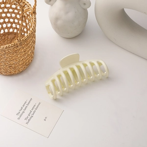 Macro shot of large cream hair claw clip with multi-tooth design on a minimalist background