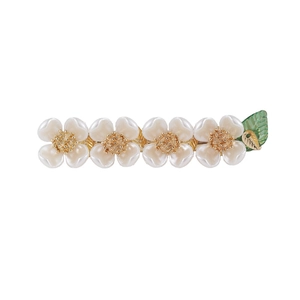 Detail of a floral hair clip with four white pearl flowers and a green leaf element