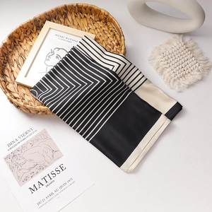 French vintage black and white striped satin silk scarf displayed on a woven basket