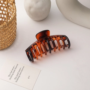 Detailed macro shot of large amber tortoise shell hair claw clip on minimalist background