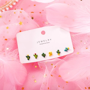 Macro shot of 6-piece cute cactus and airplane stud earrings on a pink mesh background