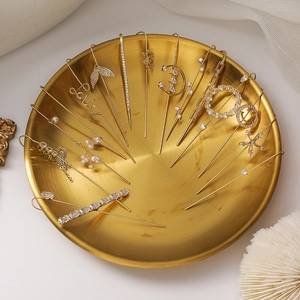 Macro view of gold crystal zircon ear cuff set with pearls in a decorative metal tray