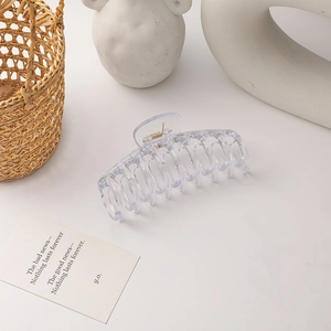 Detail of a large transparent claw clip with golden metal spring for minimalist styling