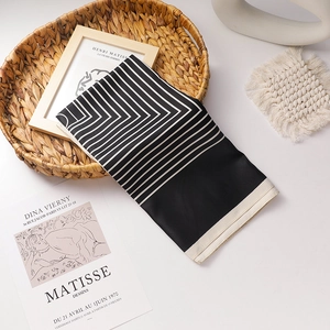 Elegant black and white striped satin silk scarf displayed in a minimalist decor tray