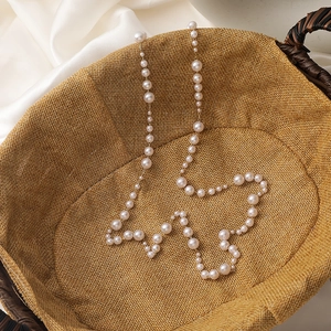 Detail of vintage beaded eyewear chain with white pearls and gold metal links on silk
