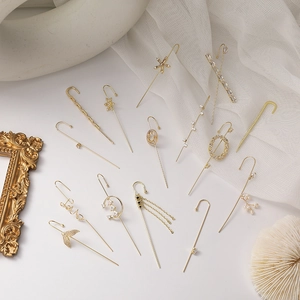 Detailed macro shot of gold-plated crystal ear cuffs and climbers on vintage decor