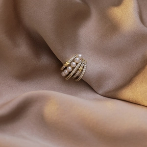 Détail de la bague d'oreille dorée à quatre couches avec perles et zircons