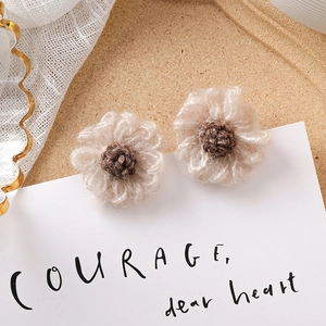 Gros plan sur les boucles d'oreilles fleurs au crochet beige et marron café