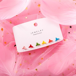 Macro detail of six pairs of colorful whale tail stud earrings on a white jewelry card