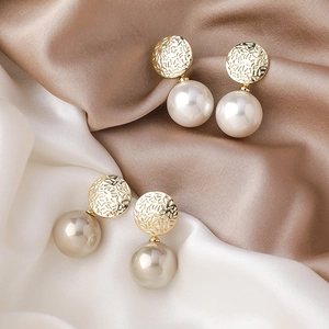 Élégantes boucles d'oreilles perles dorées avec texture martelée sur fond de soie douce