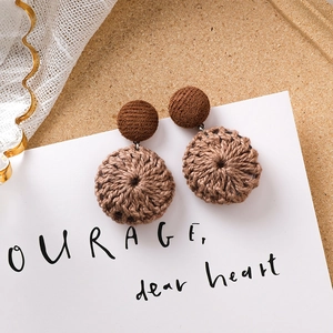 Vue détaillée de boucles d'oreilles en tricot marron avec clous sur fond vintage