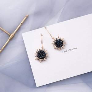 Detailed macro view of gold sunflower drop earrings with navy blue gems and rhinestones