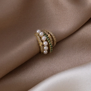 Détail macro d'un earcuff multicouche avec perles, gemmes vertes et étoile dorée