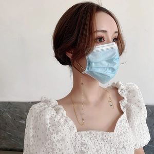 Elegante goldene Maskenkette mit bunten Perlen, getragen an einer blauen Maske